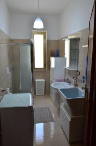 een badkamer met een wastafel, een bad en een spiegel bij La Casa del Borgo in Specchia