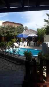 a swimming pool with two umbrellas and a table and chairs at Pousada Lazer do Sol in Lucena