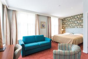 a hotel room with a blue couch and a bed at Hotel Cafe Restaurant De Gouden Karper in Hummelo