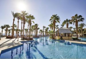 Elegant Apartment in a Luxury Resort في شرم الشيخ: مسبح بالنخيل ومبنى