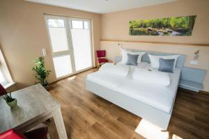 a bedroom with a white bed and a table at Burgers Hotel in Kippenheim