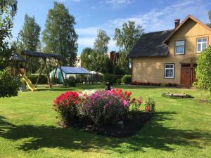 a house with a yard with a playground and flowers at Krūmiņmāja in Staicele