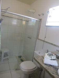 a white bathroom with a toilet and a shower at Guest House Paraiso Pataxos in Porto Seguro