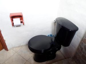 a black toilet in a bathroom with a toilet paper dispenser at Chuza Longa Home in Guamote