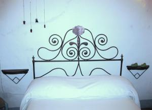 un lit avec une tête de lit en métal et une fleur sur elle dans l'établissement La casa del Rosario, à Aggius