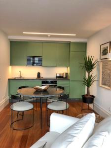 une cuisine avec des armoires vertes, une table et des chaises dans l'établissement Oporto Chic&Cozy - Aliados, à Porto