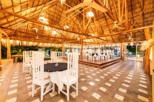 un comedor con sillas y mesas blancas en un edificio en Seis Playas Hotel, en Tamarindo