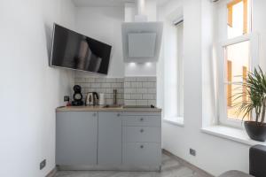 a kitchen with white cabinets and a flat screen tv on the wall at Valdemāra Apartment in Rīga