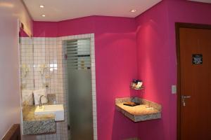 y baño de color rosa con lavabo y ducha. en Auhe Motel (Adults only), en Betim