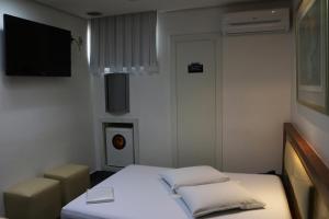Habitación pequeña con cama y TV. en Auhe Motel (Adults only), en Betim