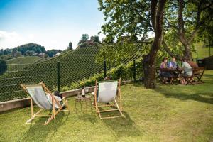 un grupo de personas sentadas en sillas en un patio en Familienweingut Oberer Germuth, en Leutschach