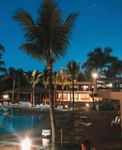 a palm tree next to a swimming pool at night at Hotel Fazenda Saint Nicolas in Águas de Lindóia