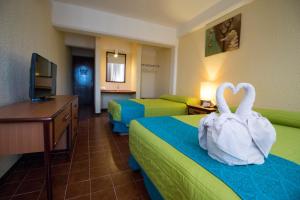 Hotel Plaza Cozumel في كوزوميل: غرفة فندق فيها بجعتين جالسين على سريرين