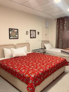 a bedroom with two beds with a red blanket at Ashel Hotel in Beer Sheva