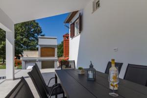 een tafel met stoelen en een fles wijn op een patio bij Lovely VILLA Piljan with a private swimming POOL in Bokordići
