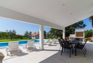 een terras met een tafel en stoelen en een zwembad bij Lovely VILLA Piljan with a private swimming POOL in Bokordići
