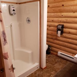 a bathroom with a shower and a toilet at Wolf Den Log Cabin Motel and RV Park in Thayne