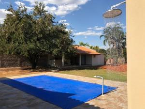 a blue swimming pool in front of a house at Cantinho do Folclore in Olímpia