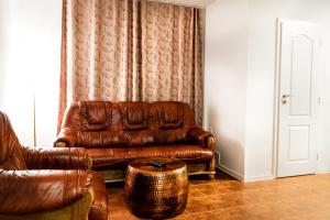 a living room with a brown leather couch and a stool at VILLA CENTRUM APARTMÁNY s RAŇAJKAMI A SAUNOU in Martin