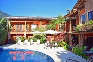 a house with a swimming pool in front of a building at Bella Ilha Pousada in Ilhabela