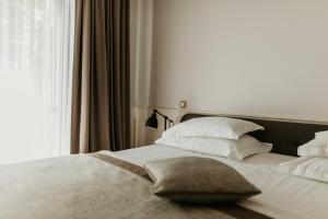 a bedroom with a bed with white pillows and a window at Hotel Majestic in Budva
