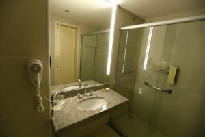 a bathroom with a sink and a shower with a mirror at Best Hotel Sobral in Sobral
