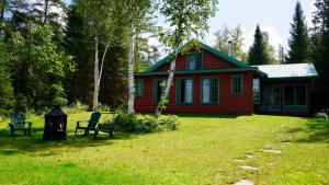 a red house with a green roof in a yard at Le Cent in Saguenay