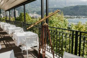 a restaurant with white tables and chairs on a balcony at Hotel Majestic in Budva