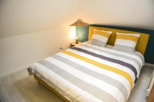 1 dormitorio con 1 cama grande con rayas amarillas y blancas en APPARTEMENT DU CENTRE, en Charleville-Mézières