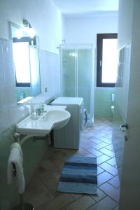 y baño blanco con lavabo y ducha. en Casa al mare La Palma, en Santa Maria Navarrese