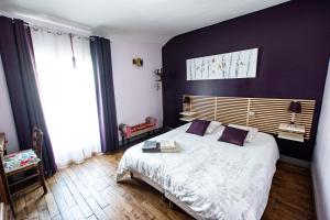 ポワティエにあるLes Trois Fontainesの紫の壁のベッドルーム1室(大型ベッド1台付)