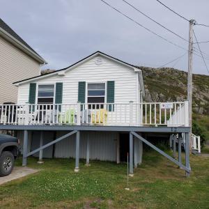 a house with a deck with chairs on it at Hillside Cottage 1 in Twillingate