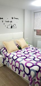 um quarto com uma cama com um edredão roxo e branco em LAIA HOME GARAJE Y WIFI em Barakaldo
