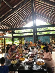 a group of people sitting around a long table with food at Residence em Muro Alto Porto de Galinhas in Porto De Galinhas