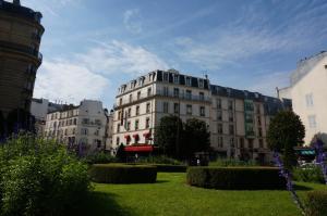 um grande edifício branco no meio de um parque em Le Bon Hôtel em Neuilly-sur-Seine