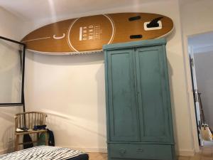 a surfboard on the wall next to a green cabinet at Can Nicasi in L'Escala