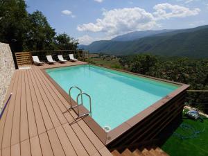 a swimming pool on a wooden deck with mountains in the background at Castello di Fagnano -Albergo Diffuso & SPA in Fagnano Alto