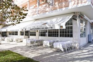 una fila de mesas y sillas frente a un edificio en Atlantic Waves Accommodation ~ Carcavelos Beach en Carcavelos