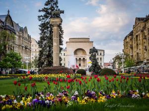 a park with flowers in front of a monument at Opera Victoriei Residence - Ultracentral Cozy accommodation in Timişoara
