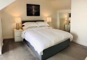 a bedroom with a large white bed with two lamps at Arran Ferry Apartment in Ardrossan