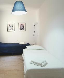 ein weißes Zimmer mit 2 Betten und einer blauen Lampe in der Unterkunft Descalzos Apartment - Old Town in Tarragona