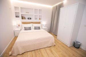 a white bedroom with a large white bed and wooden floors at Hotel Elior in Tirana