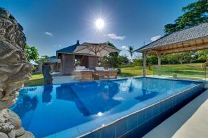 a swimming pool with a patio and an umbrella at Bali Luxury Boutique Resort and SPA in Tanah Lot