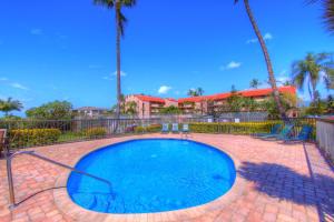 a small swimming pool with a fence and palm trees at Maui Vista 2220 in Kihei