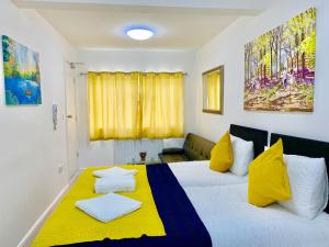 1 dormitorio con 1 cama con almohadas amarillas y blancas en 3 Bedrooms, 3 Baths, Spacious Lounge, Full Kitchen, Garden, Ground Floor, Free Parking en Londres
