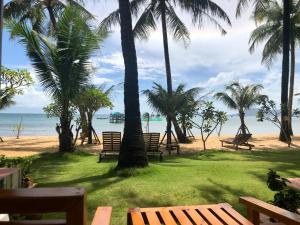 a group of benches on a beach with palm trees at Peppercorn Beach Resort in Phú Quốc