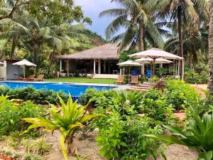 a resort with a swimming pool and palm trees at Peppercorn Beach Resort in Phú Quốc