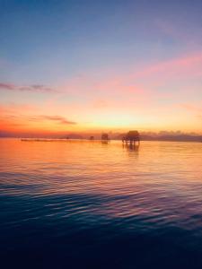 a sunset over a body of water with an island at Peppercorn Beach Resort in Phú Quốc