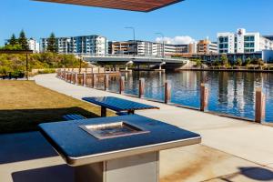 een picknicktafel naast een rivier met gebouwen bij Mercure Sunshine Coast Kawana Waters in Kawana Waters