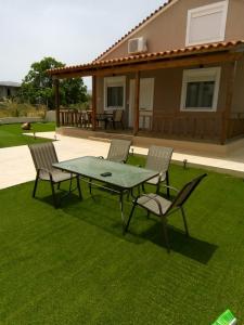 a patio with a table and chairs on the grass at Villa ARETOUSA - Cretan Hospitality in Protória